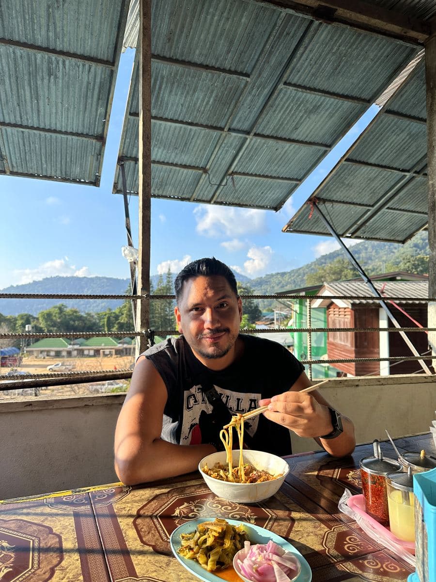 Arni eating noodles with a mountain view